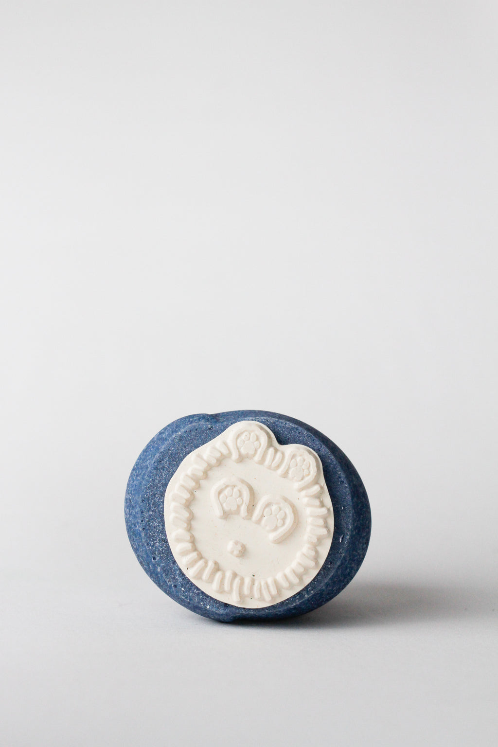 Blue and white bath bomb with a cat design on a light gray background