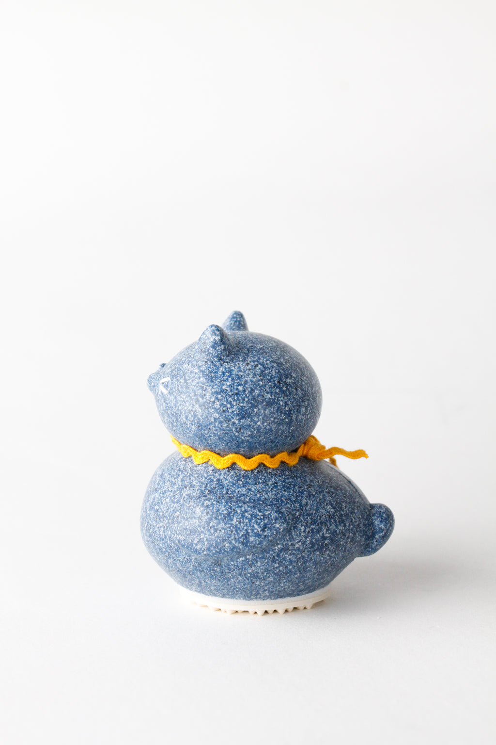 Blue ceramic duck with a yellow ribbon on a white background
