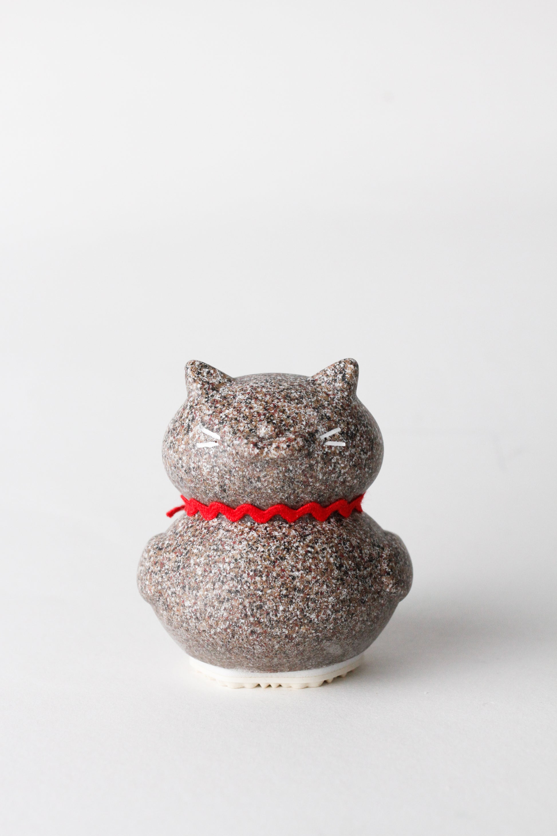 cat-shaped object with a red ribbon on a white background