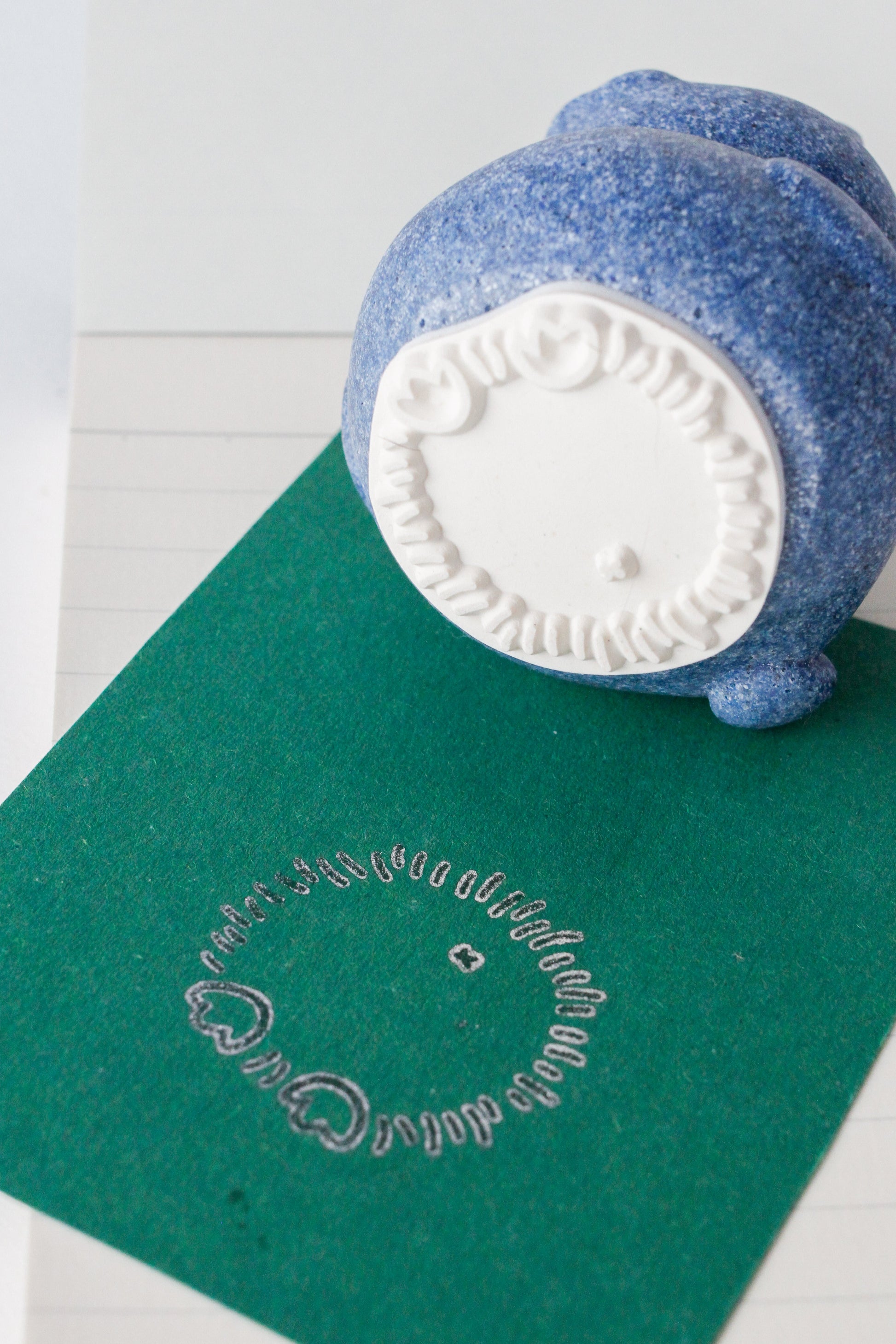 Blue stamp with a white handle on a green surface