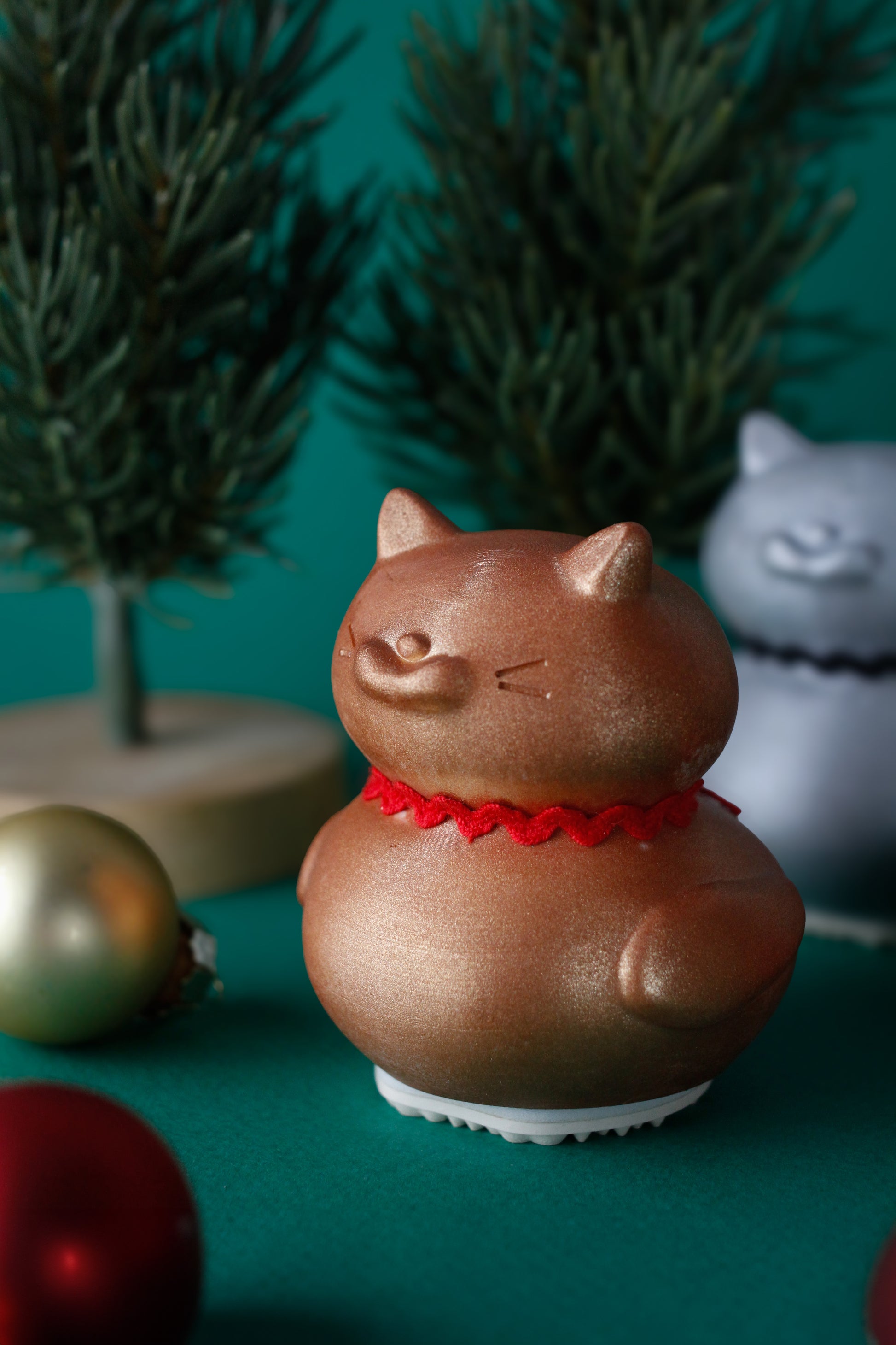 cat-shaped ornament with a red collar on a teal background