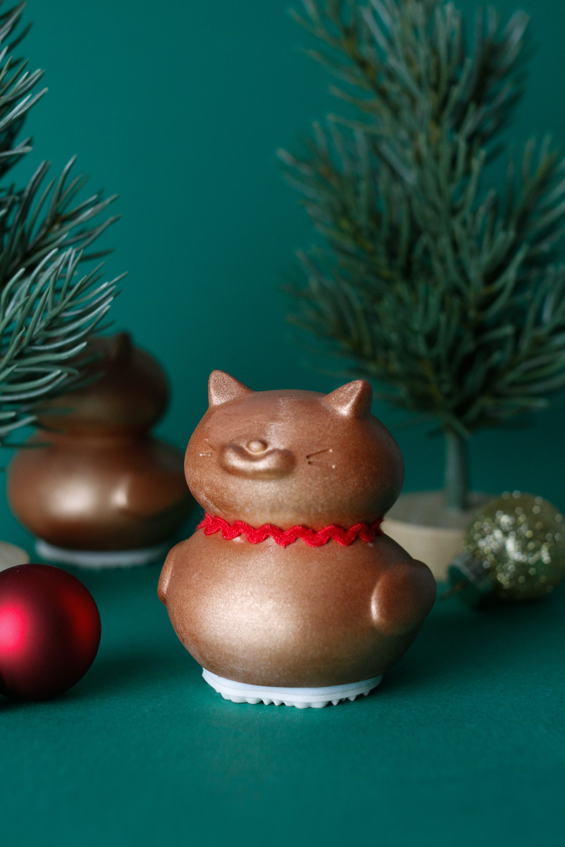  cat-shaped ornament with a red ribbon on a green background
