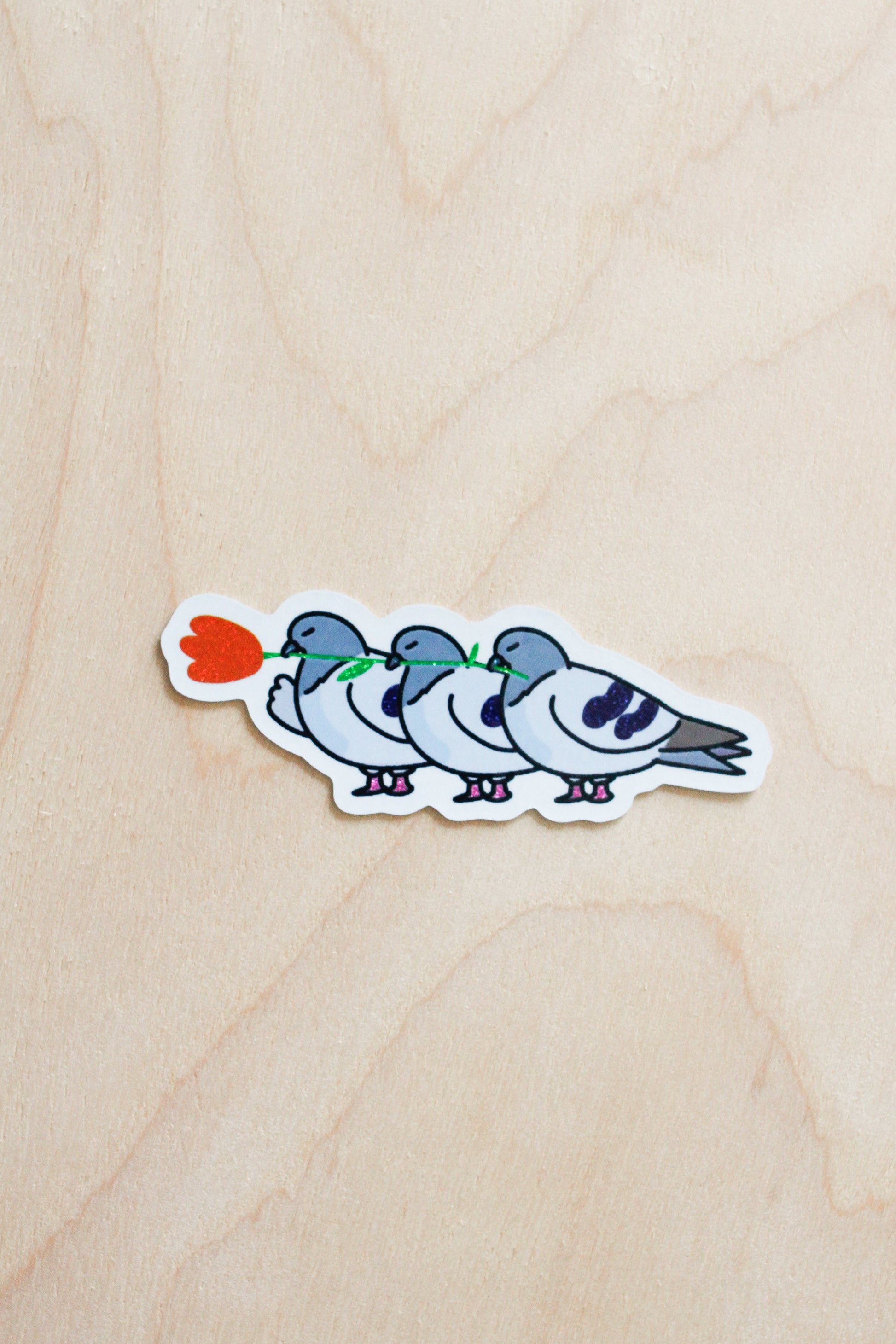 Sticker of four cartoon-style birds on a wooden surface